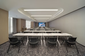 A conference room with a long table, chairs, and a large screen at the front.