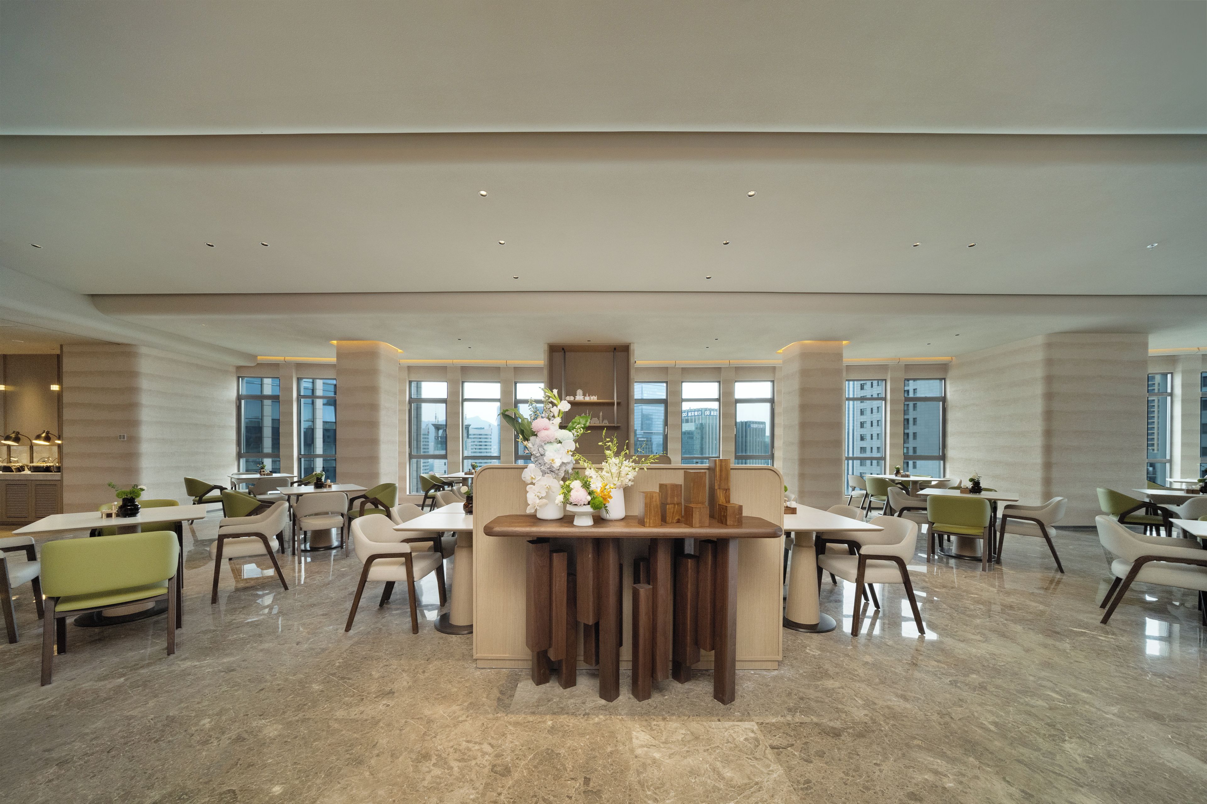 Un comedor amplio con múltiples mesas y sillas, ventanas grandes y un diseño interior moderno.