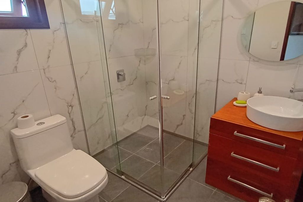 Un baño con ducha acristalada, inodoro, lavabo y espejo.