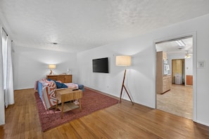 A bedroom with a bed, bedside tables, a TV, and a lamp. - Sunshine City House (St. Petersburg)