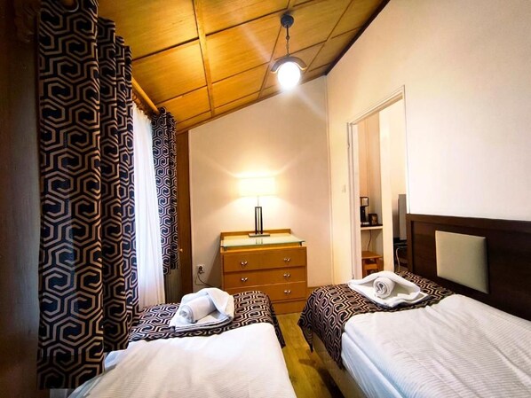 A hotel room with two beds, a dresser, a lamp, and a wardrobe.