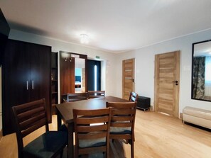 Un comedor con una mesa y sillas de madera, un armario de madera oscura y un sofá color beige.