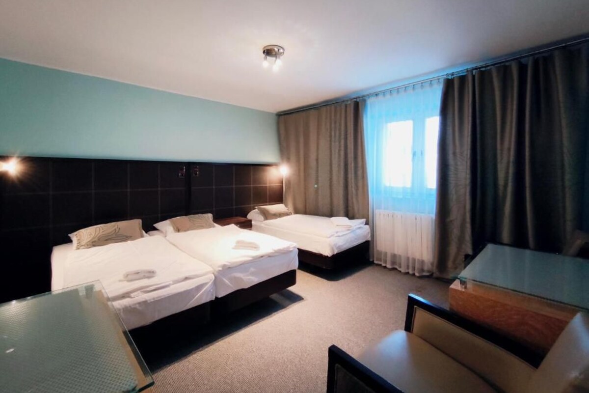 A hotel room with two beds, a desk, and a chair.