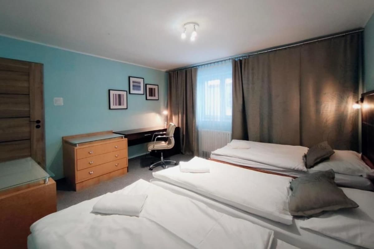 A hotel room with a bed, a desk, a chair, and a dresser.