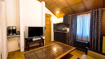 A compact living space with a television, a coffee maker, a dining table, and a kitchen area.