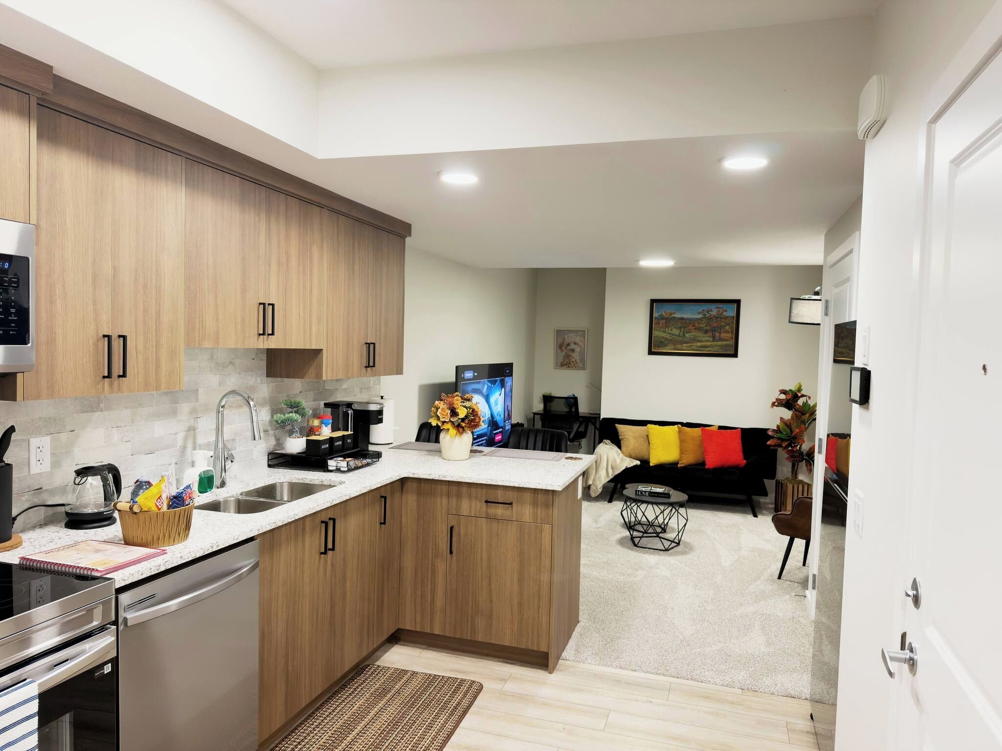 A modern kitchen with wooden cabinets, a built-in oven, and a coffee machine.