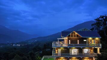 A multi-story building with balconies, a flat roof, and a view of the surrounding landscape.