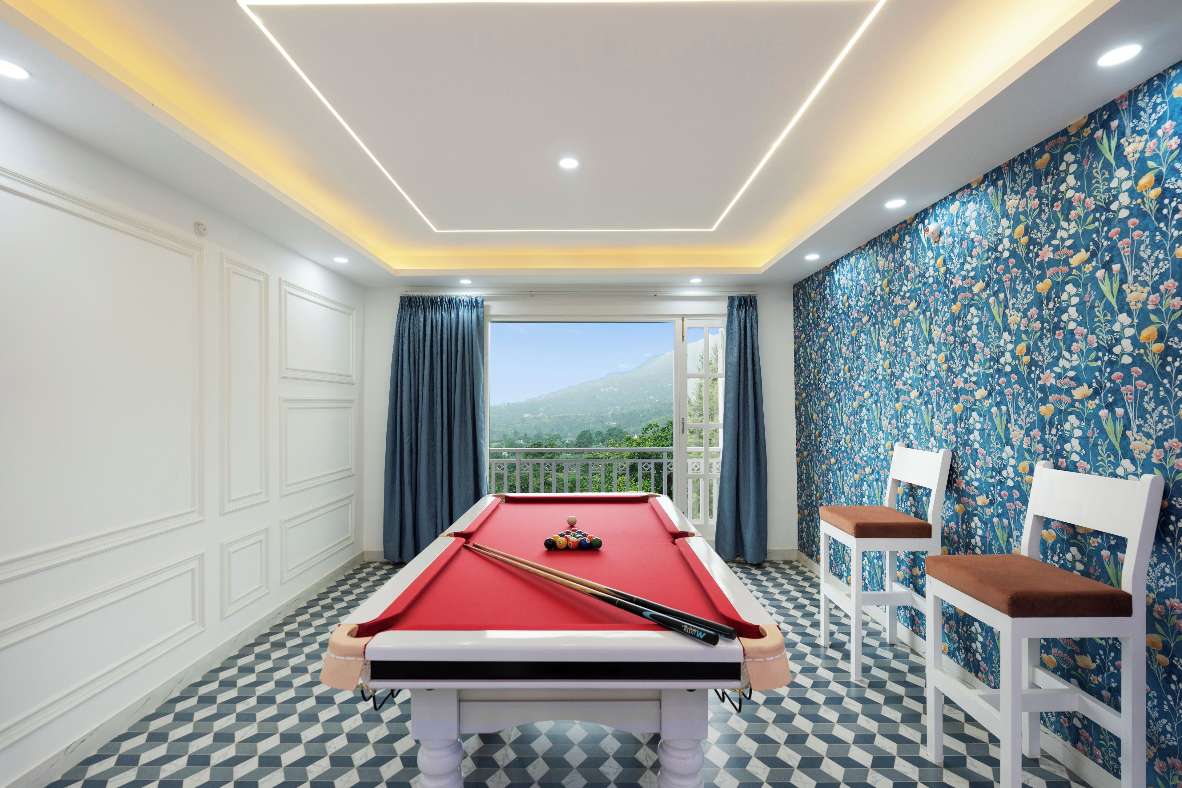 A pool table with a view of a mountainous landscape through a balcony.