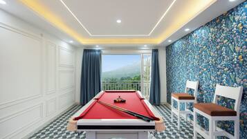 A pool table with a view of a mountainous landscape through a balcony.