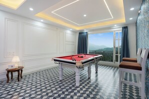 A pool table in a room with a checkered floor, a lamp, and a view of the outdoors.