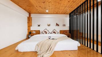 A bedroom with a large bed, wooden ceiling, white walls, and a black partition.