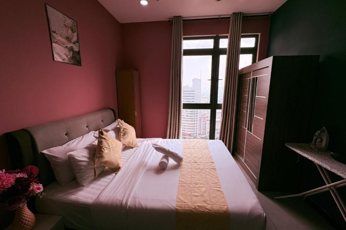 Ein Hotelzimmer mit Bett, einem Fenster mit Vorhängen, einem Flachbildfernseher und einem kleinen Tisch mit Bügelbrett.