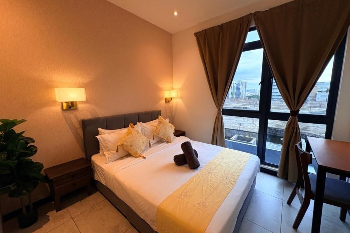 Ein Hotelzimmer mit Bett, Nachttischlampen, einem Esstisch und Blick auf die Stadt.
