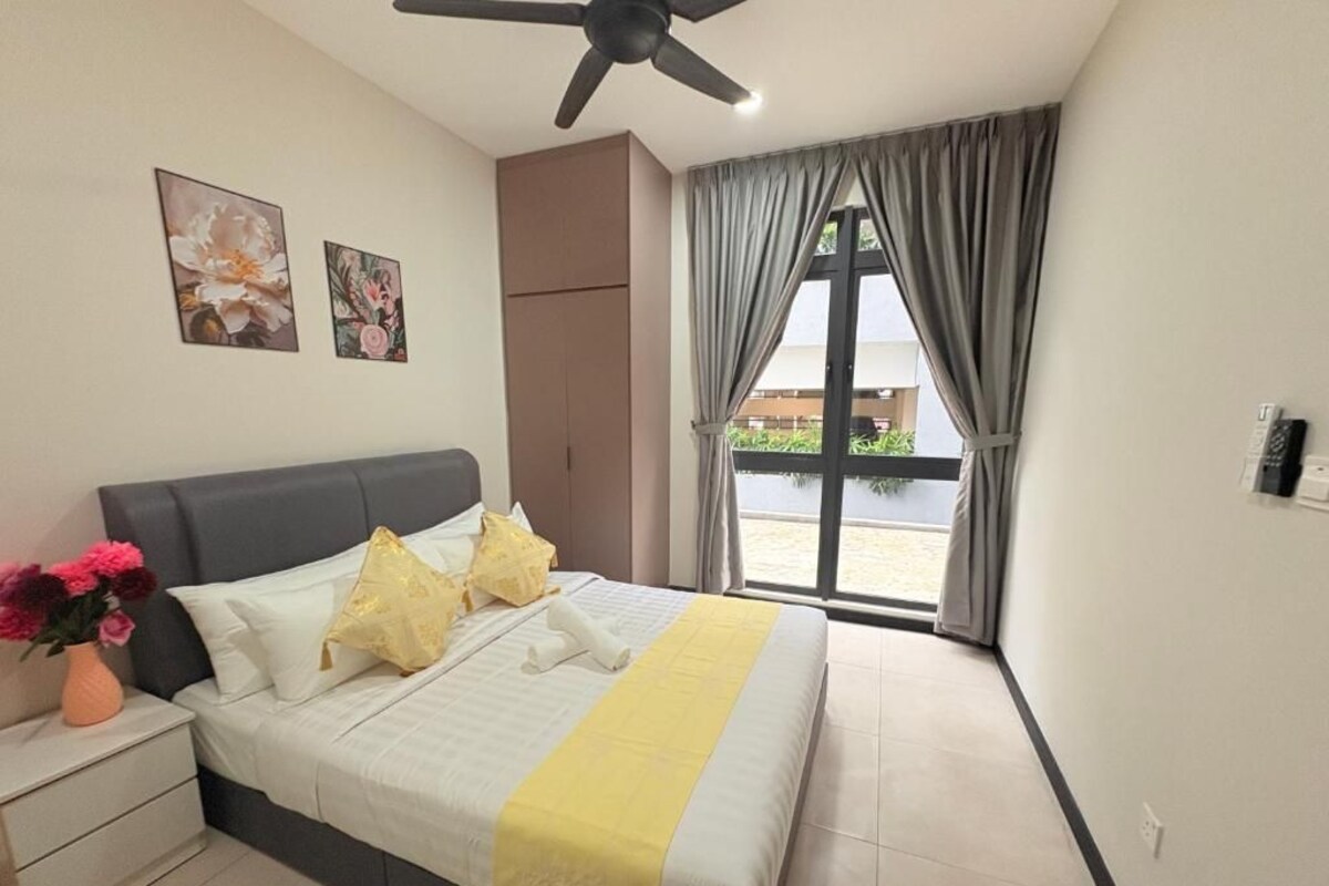 Ein Schlafzimmer mit einem Bett, einem Nachttisch, einem Deckenventilator, einem Fenster mit Vorhängen und Bildern an der Wand.