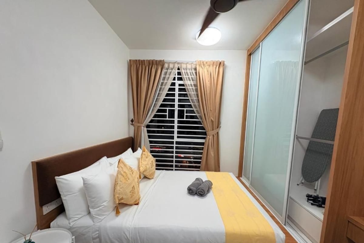 Ein Hotelzimmer mit Bett, Nachttisch, einem Fenster mit Vorhängen und einer Schiebetür zu einer Duschkabine.