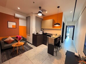 A modern living space with a sofa, coffee table, and a dining area with chairs. - Neu suite Family Room By Rasbo Galaxy (Kuala Lumpur)