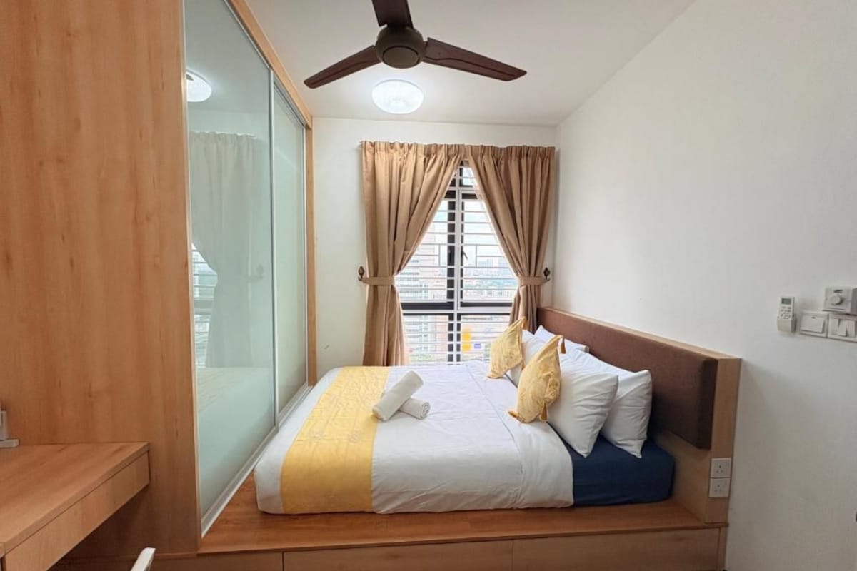 Ein Schlafzimmer mit einem Bett, einem Deckenventilator, einem Fenster mit Vorhängen und einem Nachttisch.