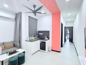 Un appartement moderne doté d’une kitchenette, d’un canapé, d’une table à manger et d’un ventilateur de plafond.