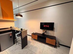 A modern kitchen with a built-in refrigerator, a dining area with a chair, and a wall-mounted television displaying 'NETFLIX'. - Neu suite Family Room By Rasbo Galaxy (Kuala Lumpur)