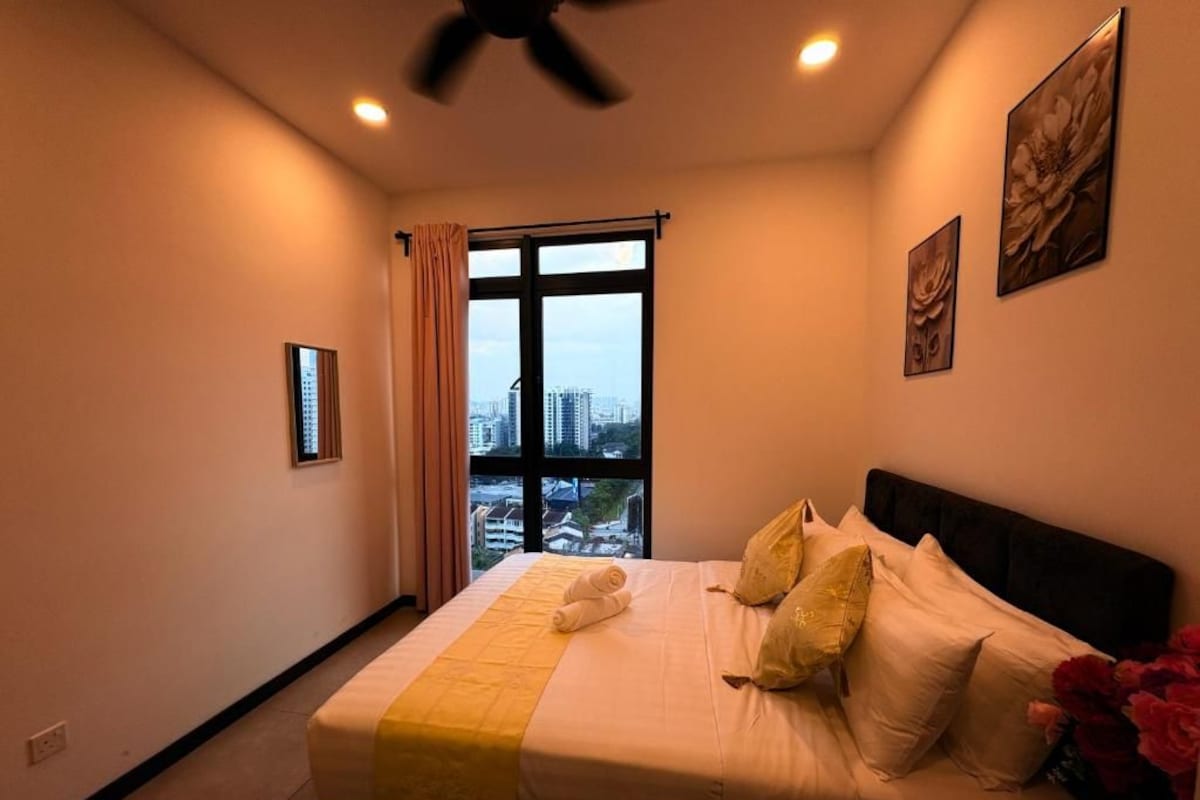 Ein Hotelzimmer mit einem Bett, einem Deckenventilator, einem Fenster mit Vorhängen und Blick auf die Stadt.