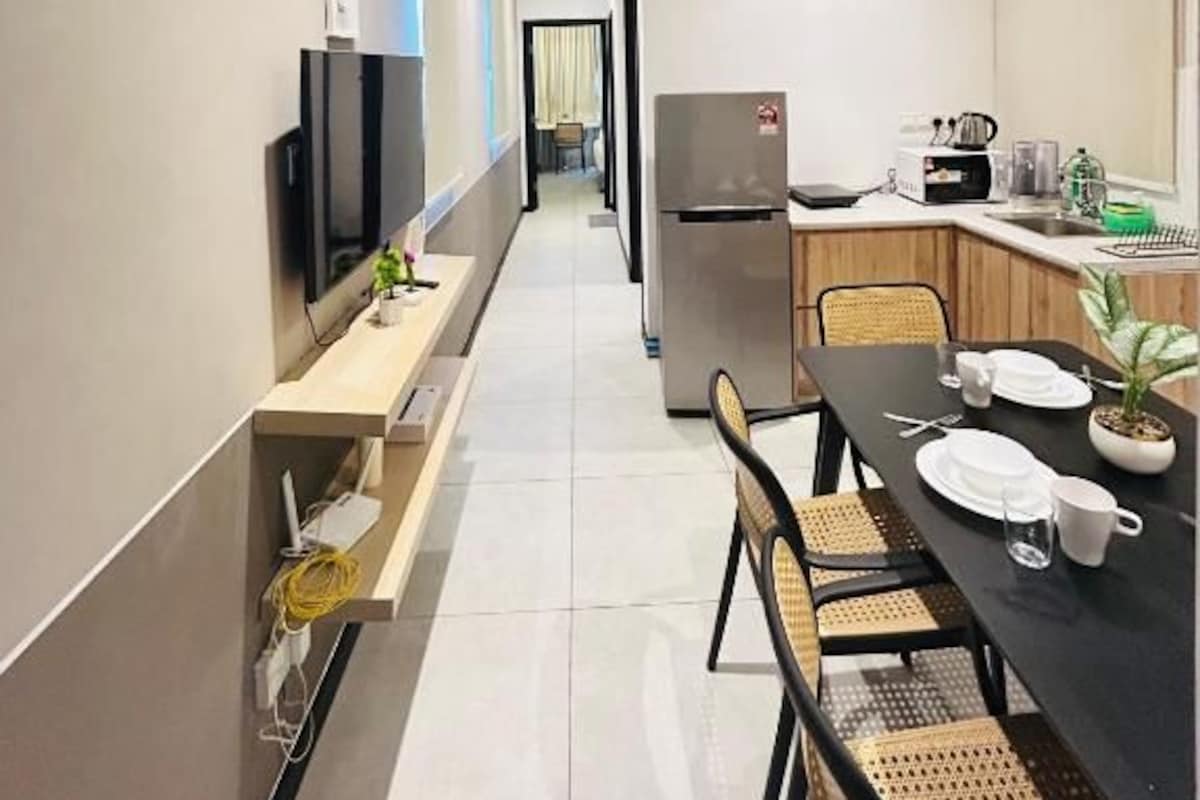 Eine moderne Küche mit Kühlschrank, Herd und Essbereich mit Stühlen und Tisch.