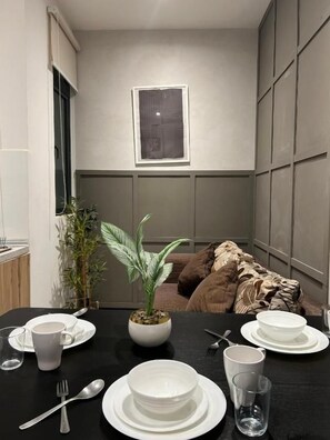 A dining area with a table set for two, a potted plant, and a window above the table. - Neu suite Family Room By Rasbo Galaxy (Kuala Lumpur)