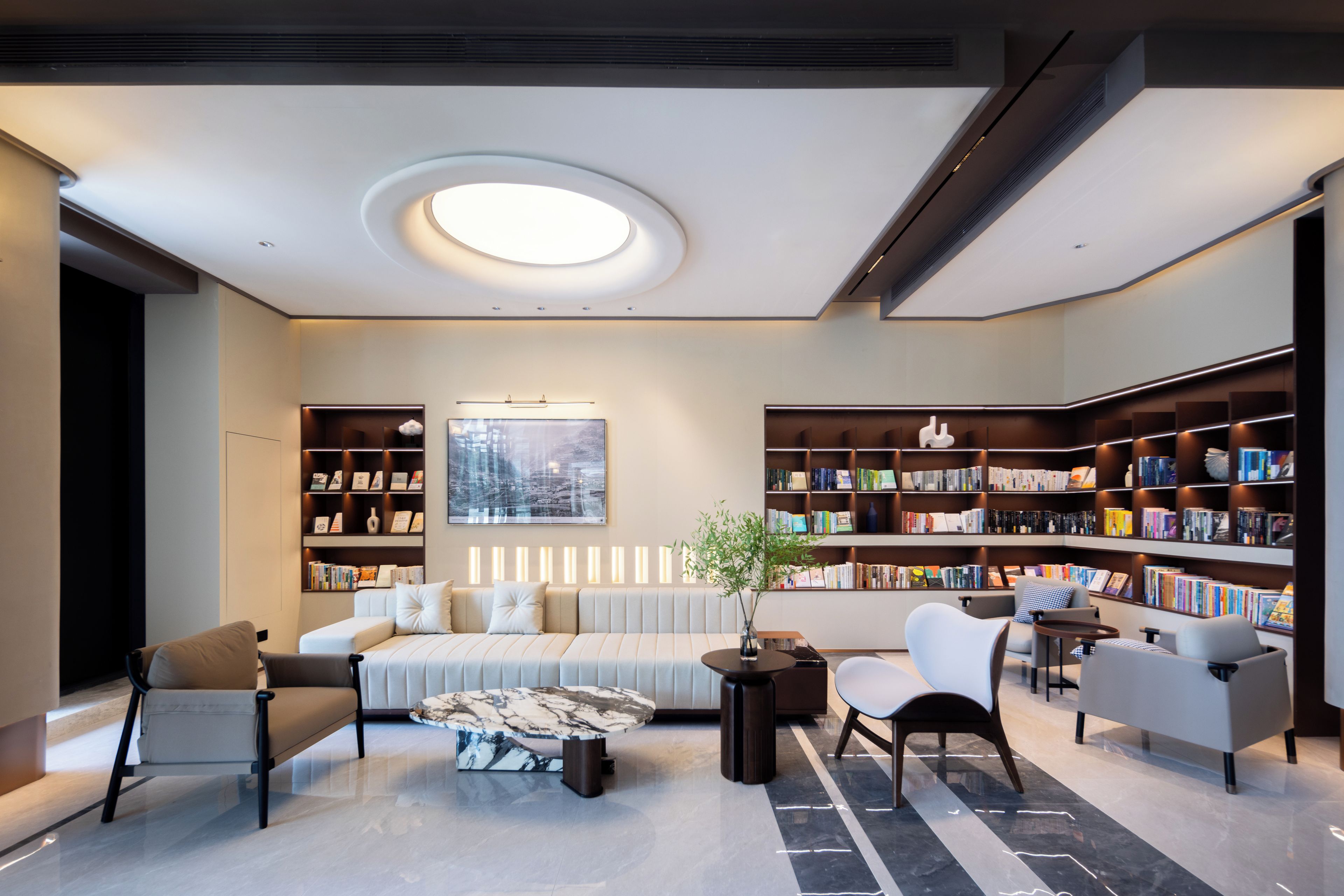 Una biblioteca moderna con un sofá, sillas y estanterías.