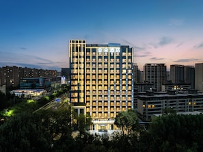 Un hotel alt amb nombrosos pisos, una entrada destacada i una façana ben il·luminada.