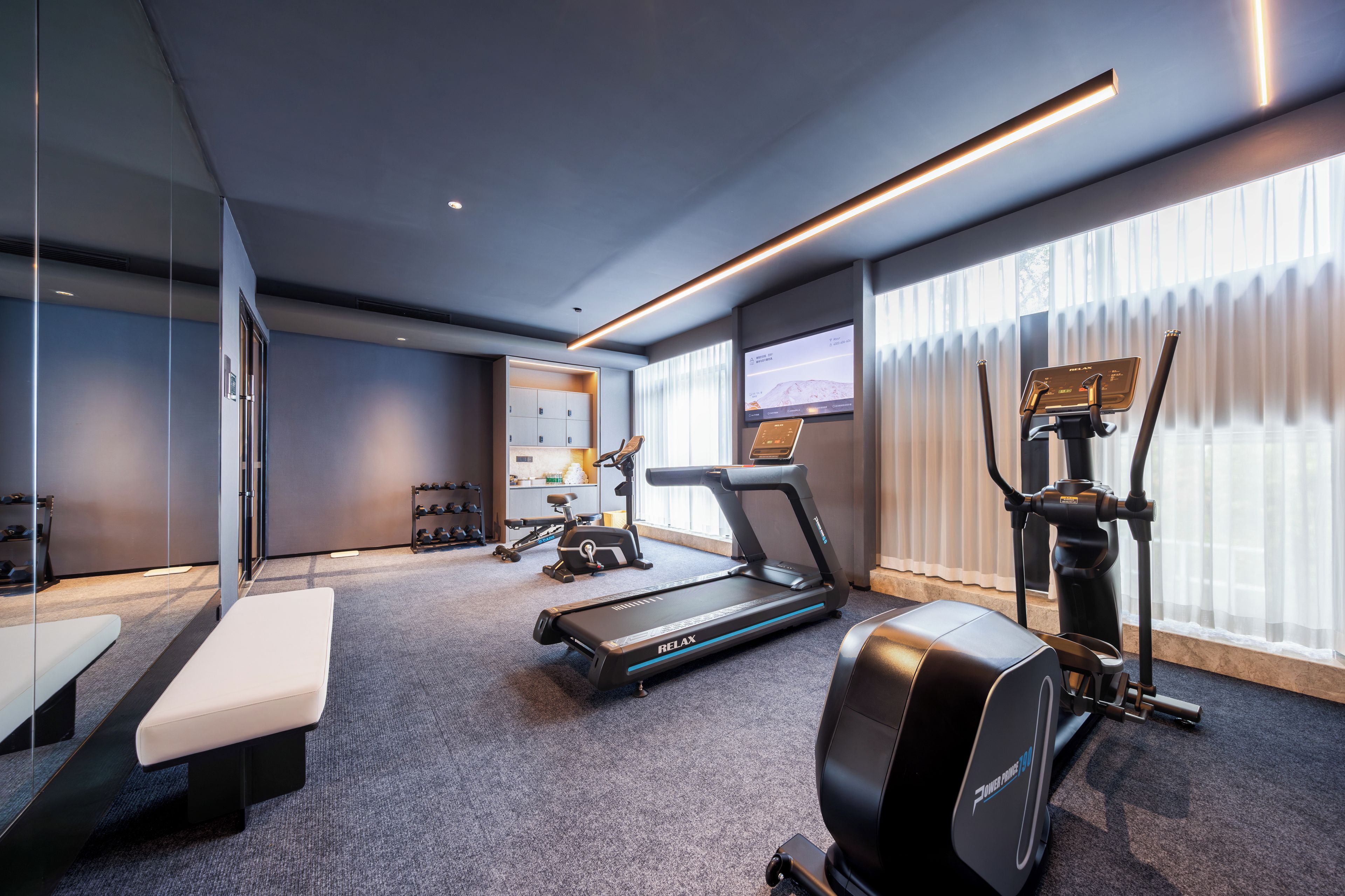 Un gimnasio moderno con cinta de correr, elíptica y bicicleta estática.