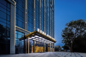 A modern hotel entrance with a glass facade and illuminated signage. - Atour Hotel  Shenbei Wanda Plaza (Shenyang)