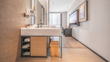 Un baño moderno con un espejo grande, un lavamanos y una zona de ducha.