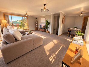 Ein modernes Wohnzimmer mit einer Couch, einem Esstisch und Blick ins Freie.