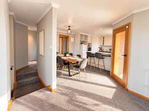 A modern interior with a dining area, kitchen, and staircase. - Wallcrest Retreat | 5BR, Views, Pets & Parking (Berriedale)