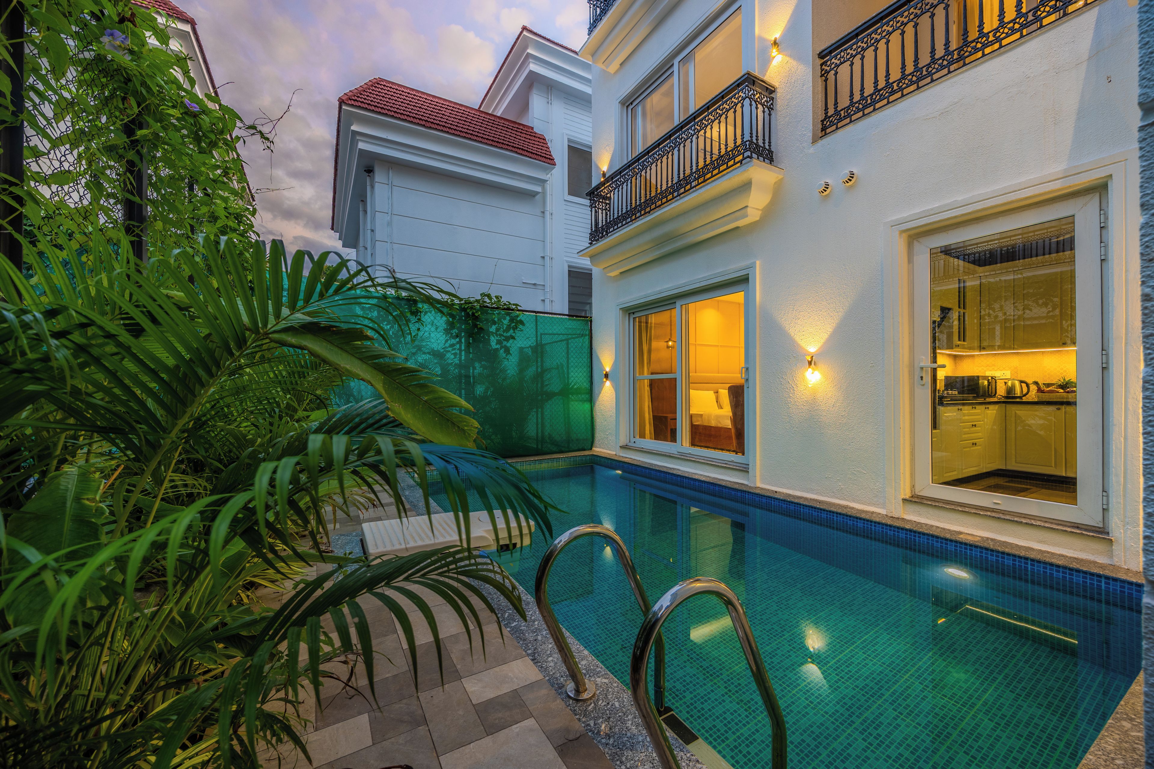 A residential building with a swimming pool, a balcony with a railing, and a view of the adjacent property.