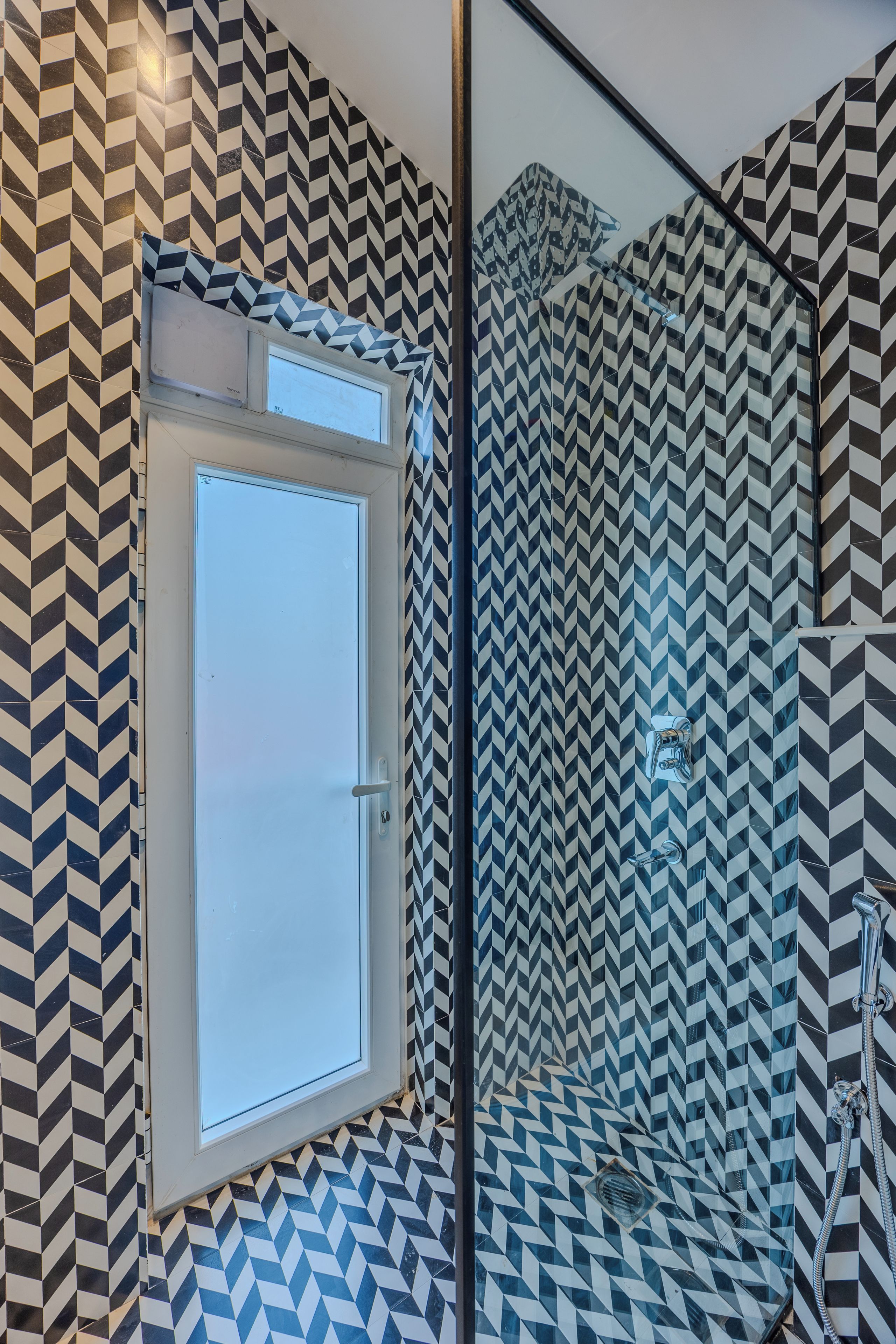 A bathroom with a geometric patterned tile design, a door, and a shower area.