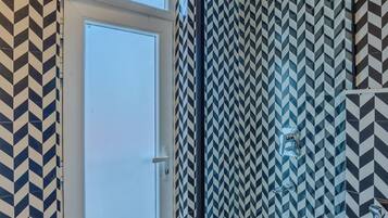 A bathroom with a geometric patterned tile design, a door, and a shower area.