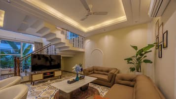 A spacious living area with a sofa, television, and a staircase.