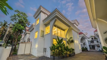 A modern two-story house with a large bay window, a gated entrance, and a paved driveway.