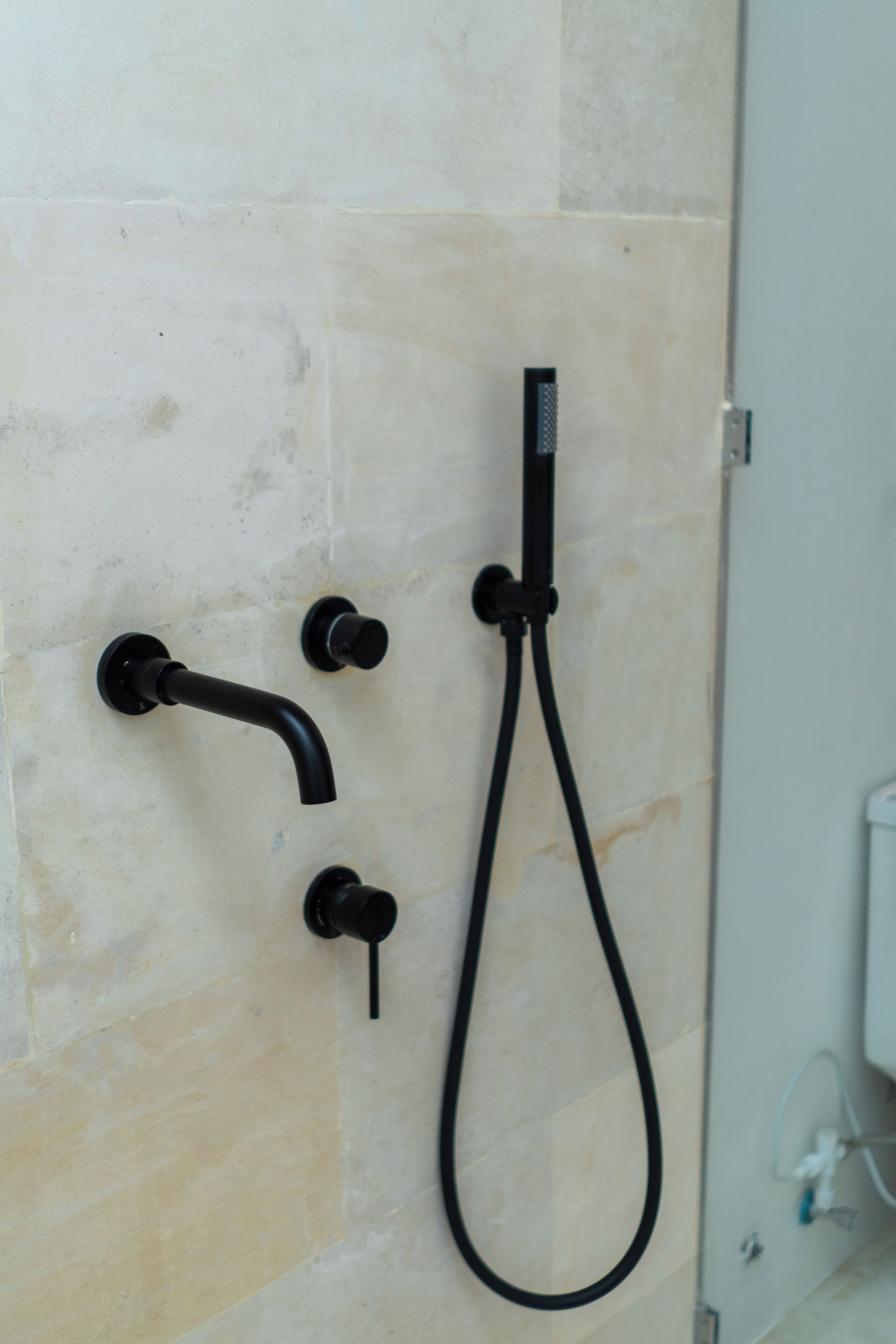 Un baño con cabezal de ducha, ducha de mano y grifo empotrado.