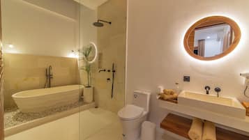 A modern bathroom with a freestanding bathtub, a toilet, a sink with a wooden vanity, and a mirror with a wooden frame.