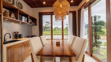 A modern kitchen with a dining area, wooden ceiling, and large windows.