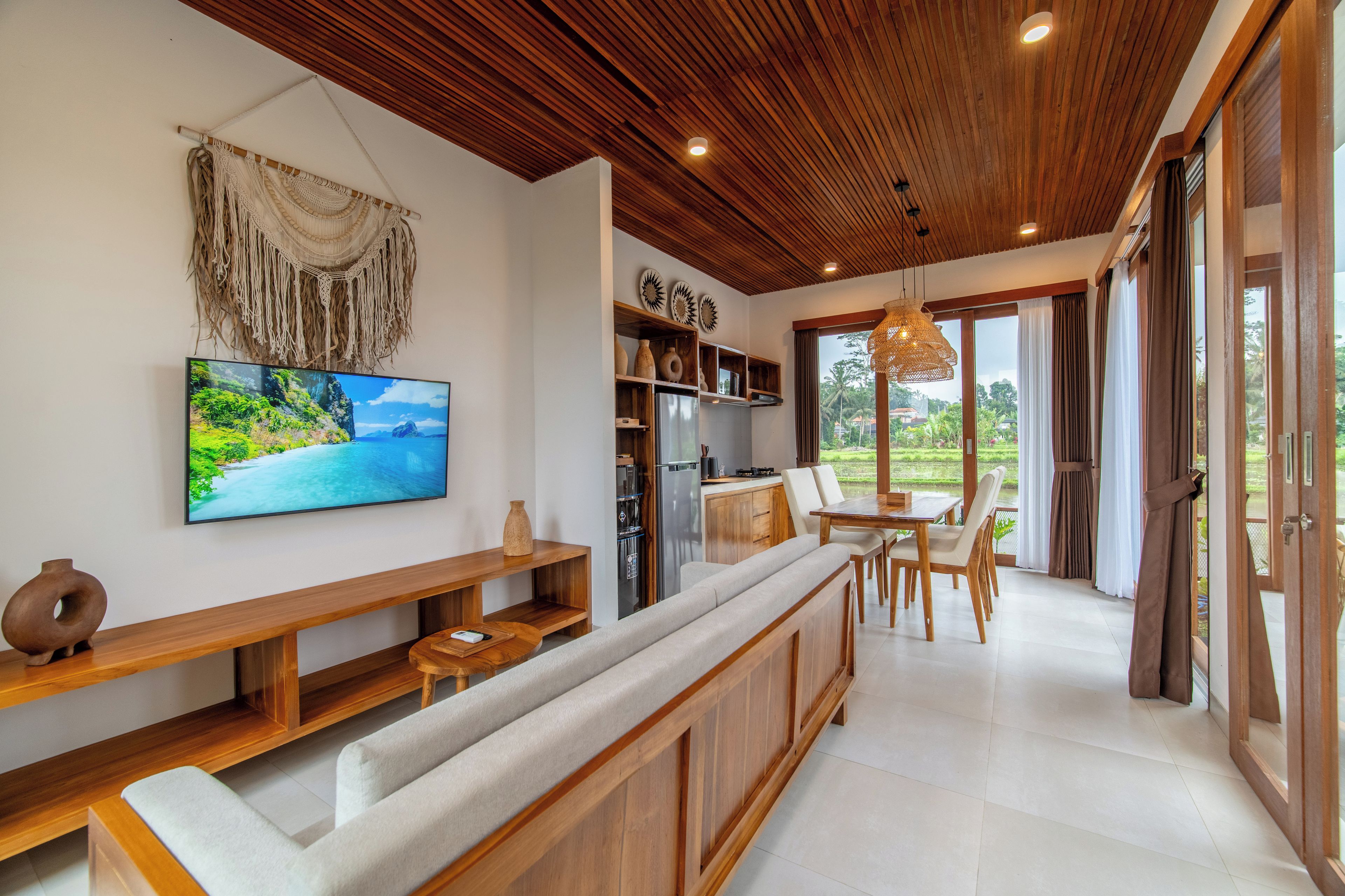 Una sala moderna con televisor de pantalla plana, muebles de madera y vistas al exterior.