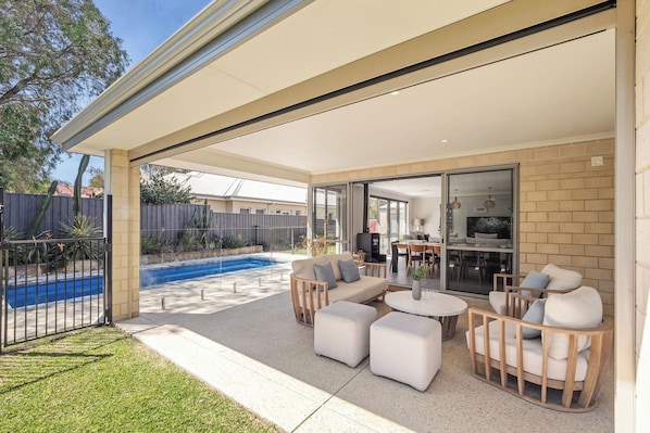 Eine überdachte Terrasse im Freien mit Sitzgelegenheiten und einem Pool.