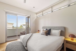 A bedroom with a large bed, a chair, a nightstand, and a view of the outside. - Bayview on Smith—Poolside Sanctuary & Ocean Vistas (Dunsborough)