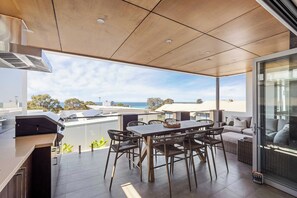 A modern outdoor dining area with a view of the sea, equipped with a grill and seating. - Bayview on Smith—Poolside Sanctuary & Ocean Vistas (Dunsborough)