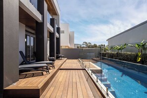 A modern outdoor pool area with wooden decking, lounge chairs, and a clear view of the pool. - Bayview on Smith—Poolside Sanctuary & Ocean Vistas (Dunsborough)