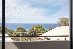 A view of the sea from a window overlooking a residential area with trees and a clear sky. - Bayview on Smith—Poolside Sanctuary & Ocean Vistas (Dunsborough)
