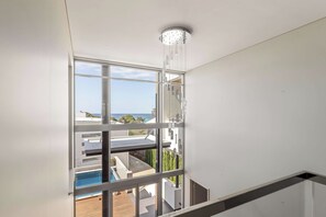 A modern interior with a large window overlooking a pool and a view of the sea. - Bayview on Smith—Poolside Sanctuary & Ocean Vistas (Dunsborough)