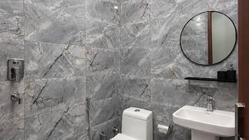 Une salle de bain avec des toilettes, un lavabo et une douche.