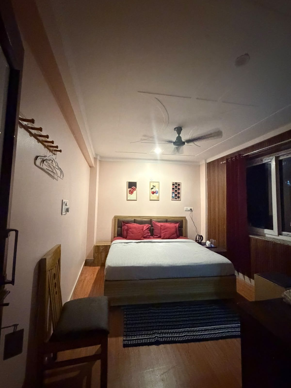 A bedroom with a bed, a ceiling fan, a window, and a nightstand.